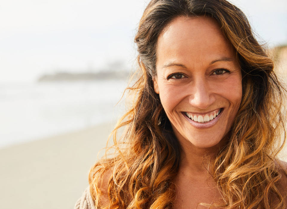 Smiling mature woman standing on a sandy beach